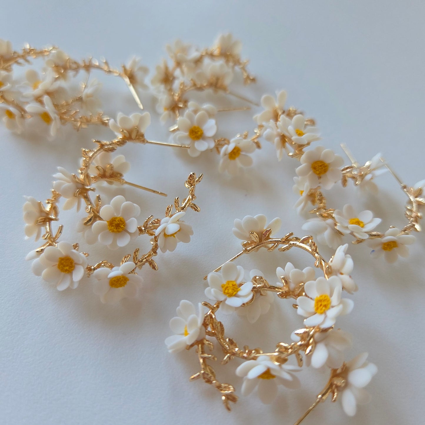 Floral hair accessories with white flowers and gold leaves on a light background