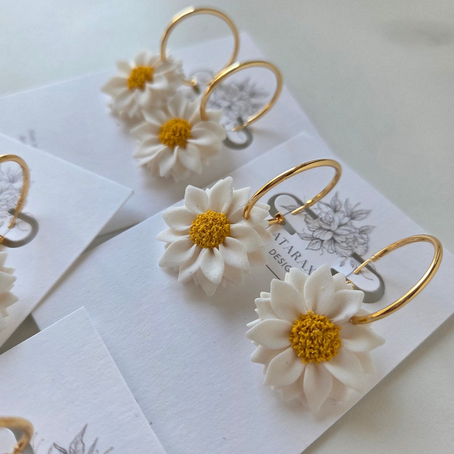 White flower earrings with gold loops on a white background