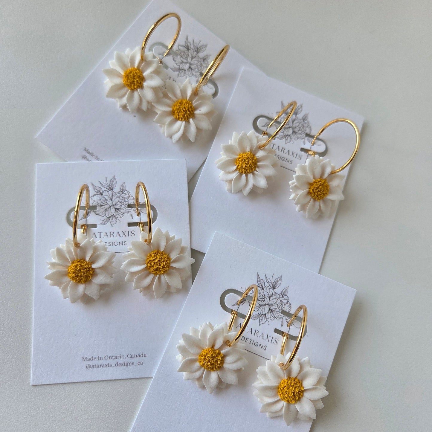 Floral earrings on branded cards with a white background