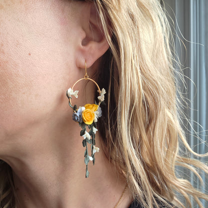 Close-up of a floral earring worn by a person with blonde hair.