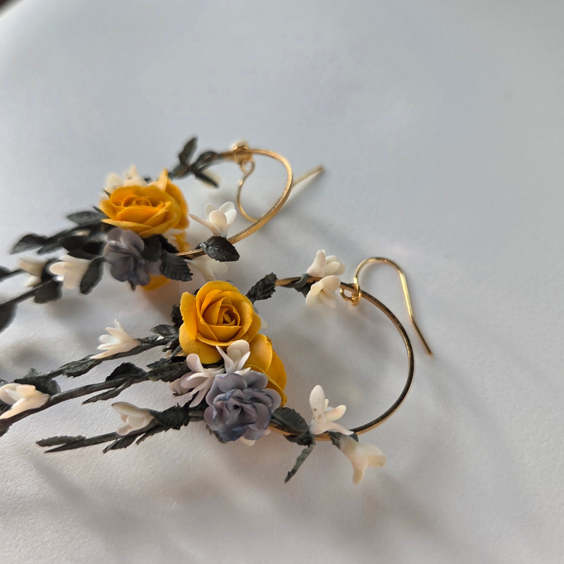Floral earrings with yellow and purple flowers on a light gray background