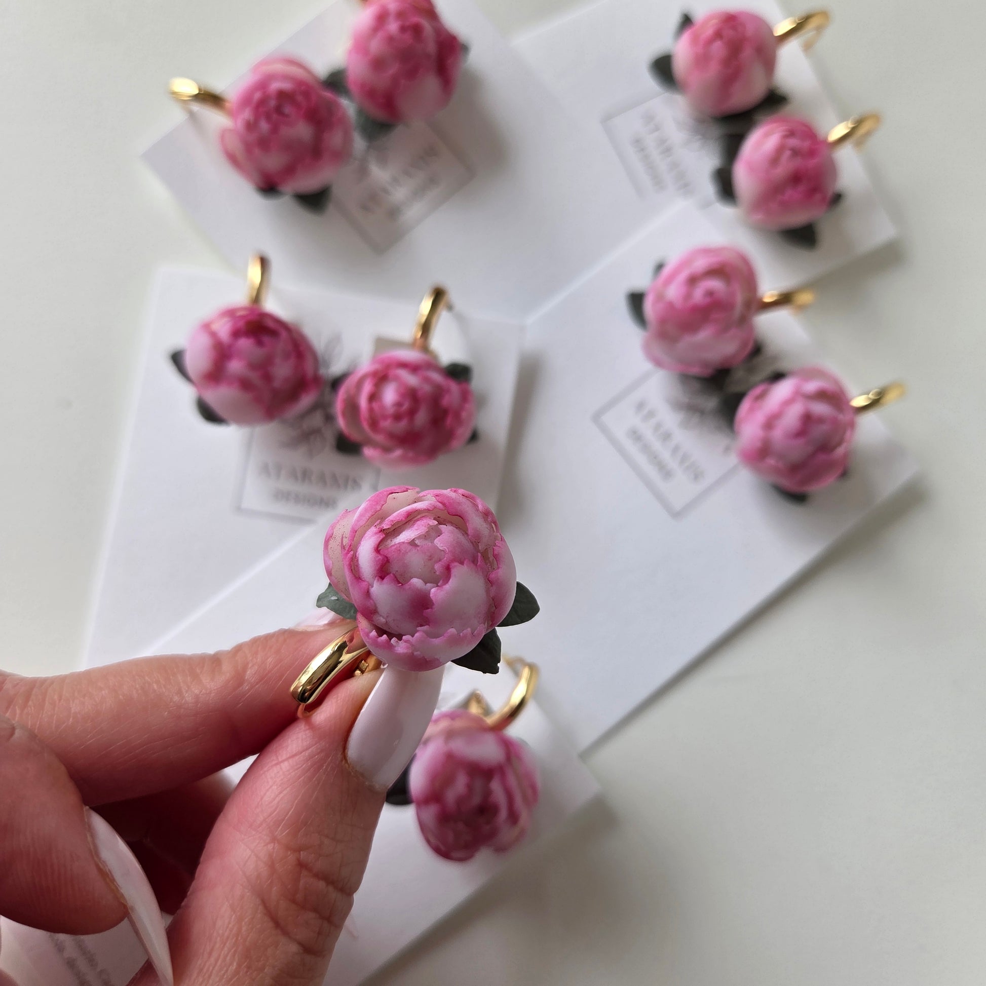 Pink floral hair clips on a white card with a hand holding one clip.