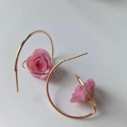 Gold hoop earrings with pink roses on a white background