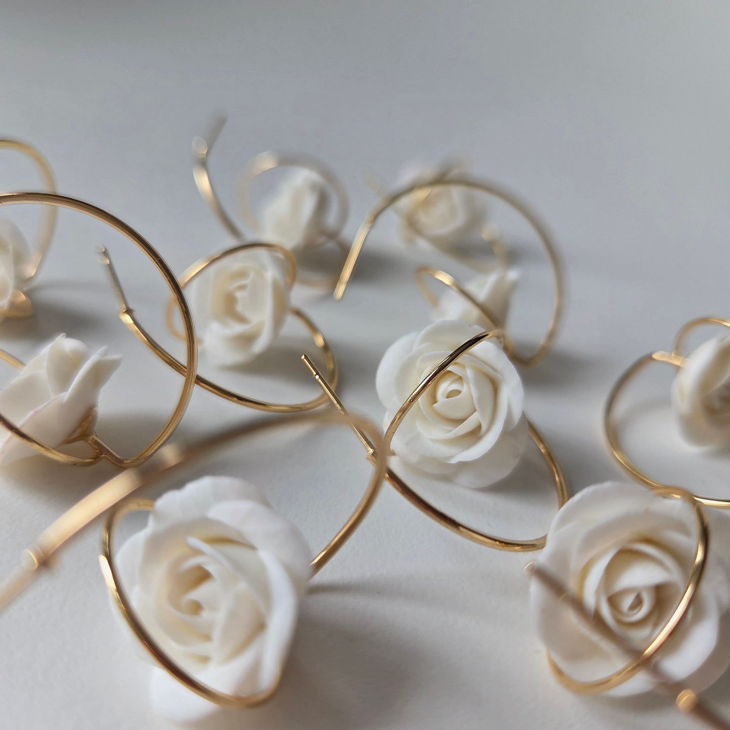 Decorative arrangement of white roses with gold 14K gold hoop earrings 