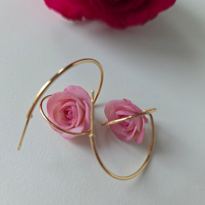 Gold hoop earrings with pink roses on a white background