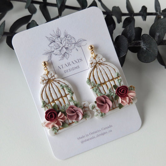 Floral-themed earrings on a branded card with greenery in the background