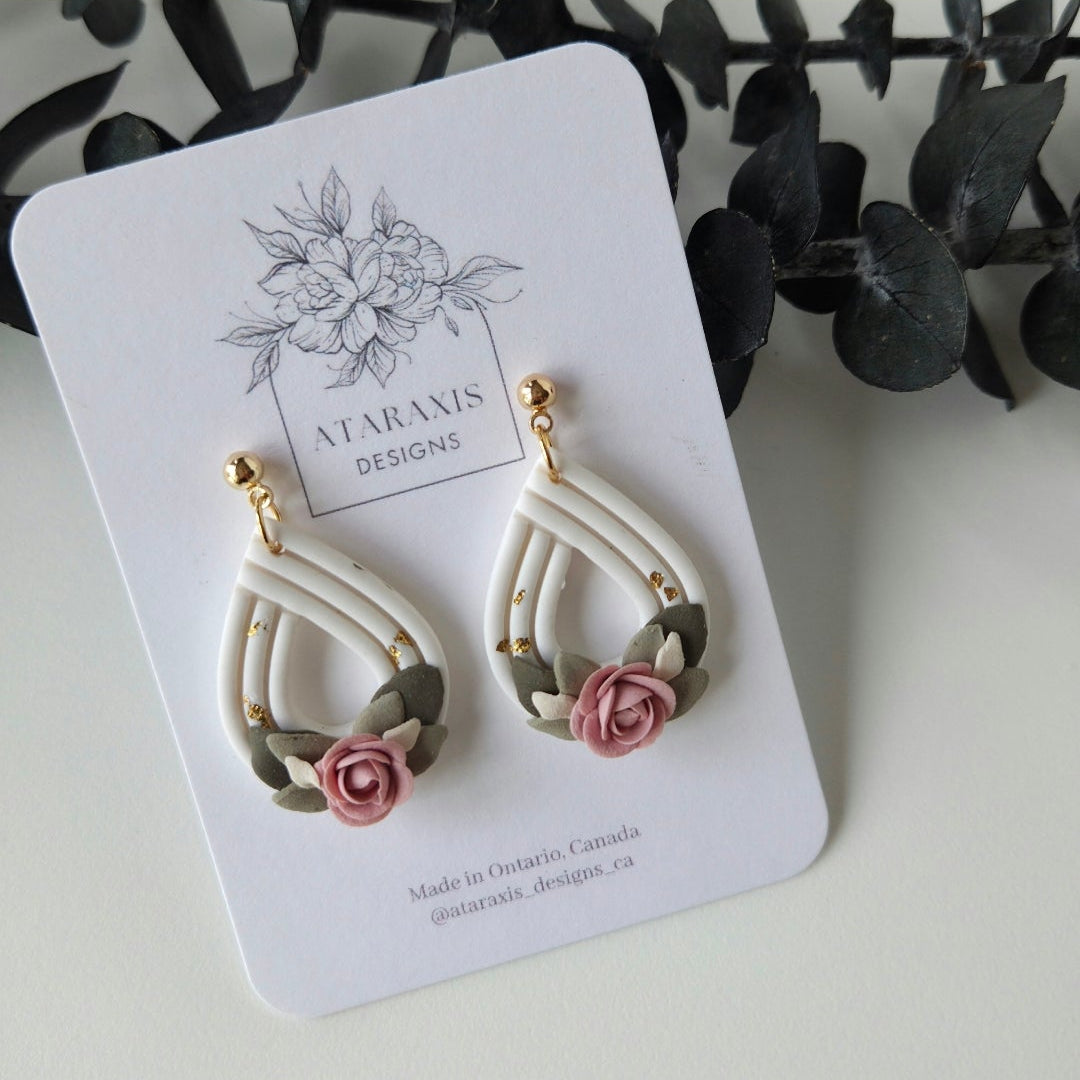 Pair of earrings on a card with floral design, displayed on a white background.