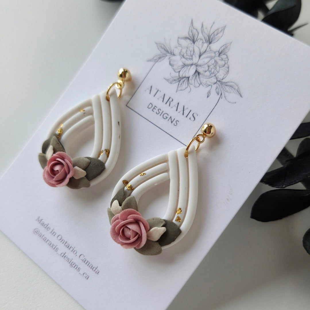 Pair of floral earrings on a white card with a floral design, displayed on a smartphone screen.