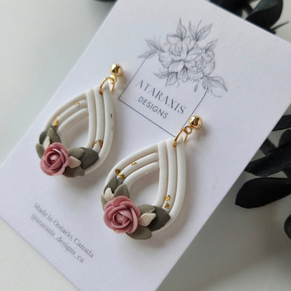 Pair of floral earrings on a white card with a floral design, displayed on a smartphone screen.